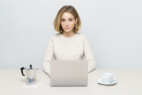 Attraktives mädchen, das an laptop beim trinken des kaffees arbeitet