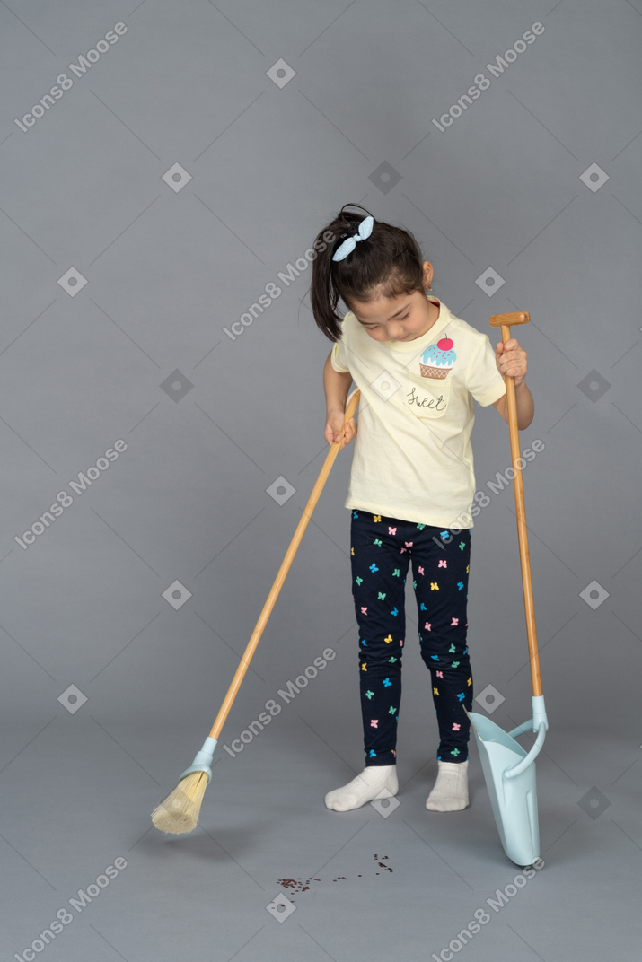 Little girl sweeping dirt off the floor