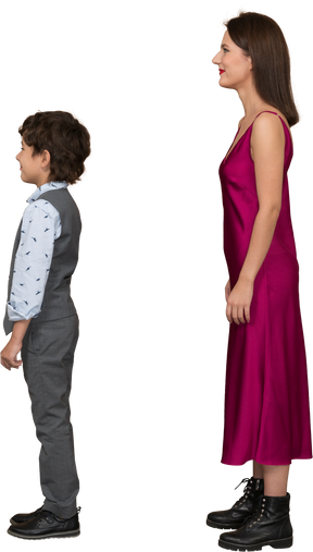 Stylsih woman in red dress and boy in suit vest standing in profile