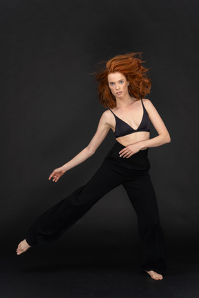 A frontal view the young beautiful girl posing on the black background looking to the camera