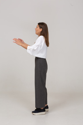 Vista laterale di una giovane donna scioccata in abiti da ufficio che alza la mano