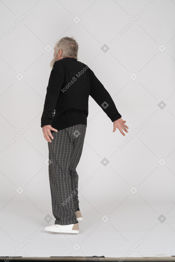 Пожилой мужчина стоит с вытянутыми назад руками