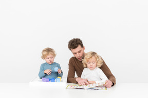 Padre jugando y leyendo con sus hijos