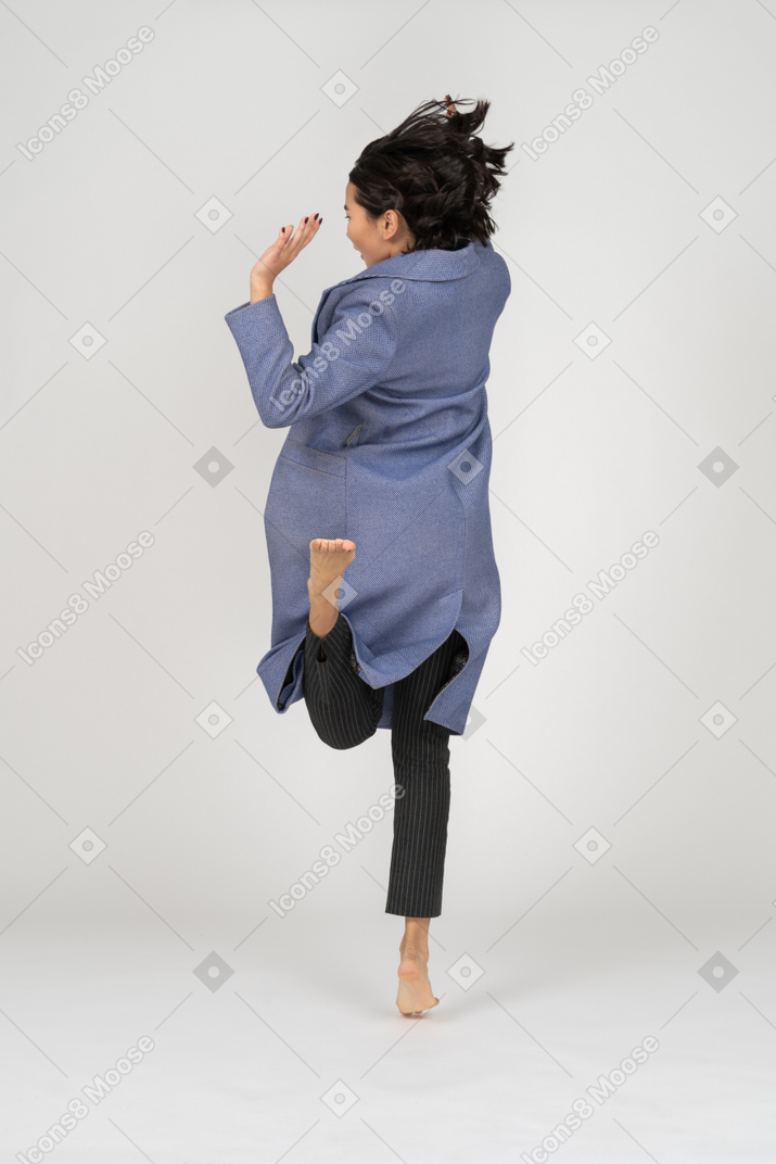 Punto di vista posteriore della donna che salta su una gamba