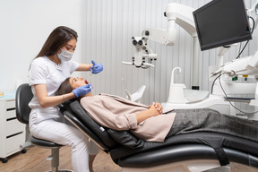 Full-length of a female dentist making an injection to her patient in a hospital cabinet