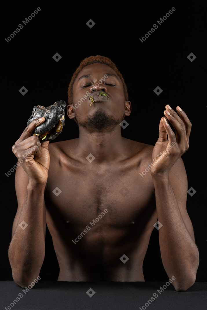 Вид спереди молодого афро-мужчины, наслаждающегося гамбургером