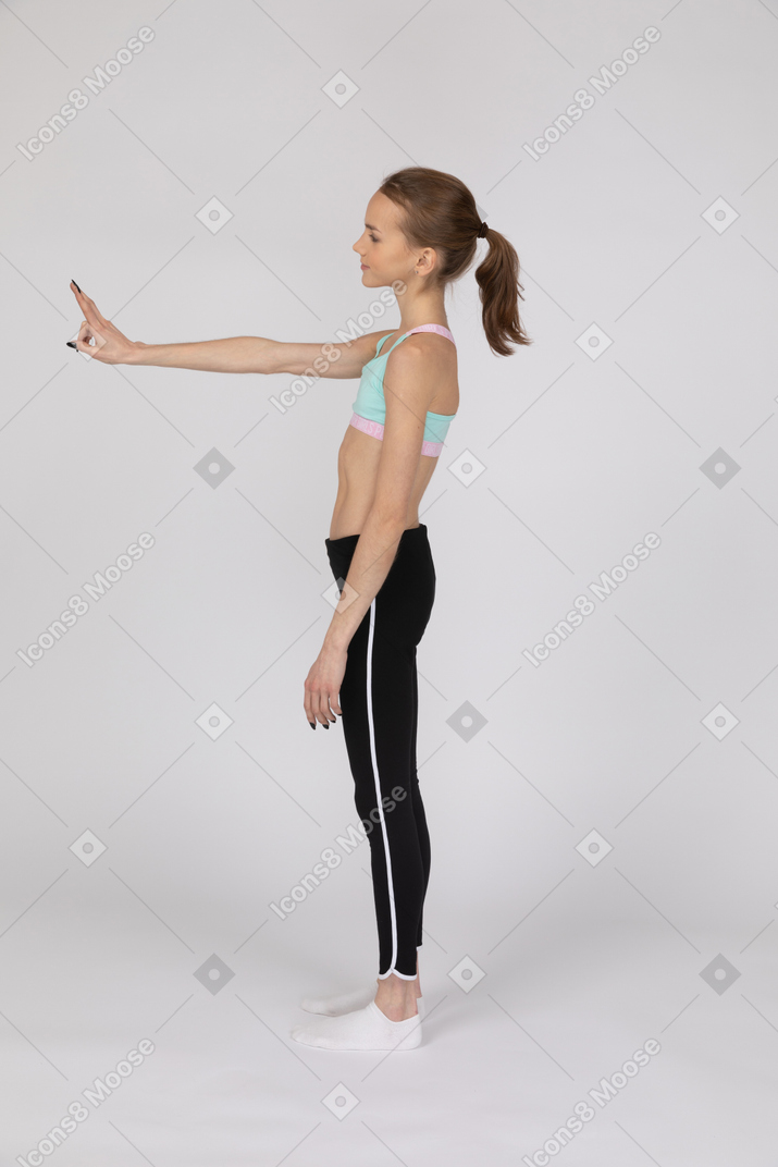 Side view of teen girl in sportswear showing peace sign