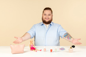 Grande homem sentado à mesa com brinquedos nele com os braços abertos