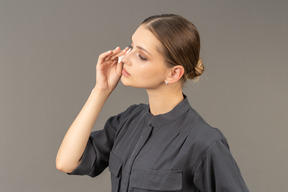 Three-quarter view of a young woman in a jumpsuit removing eye make-up