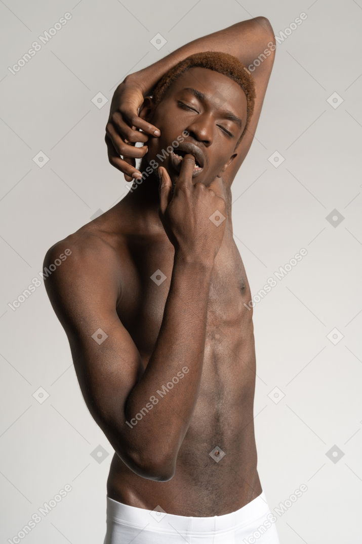 Homem de topless com os olhos fechados tocando o lábio