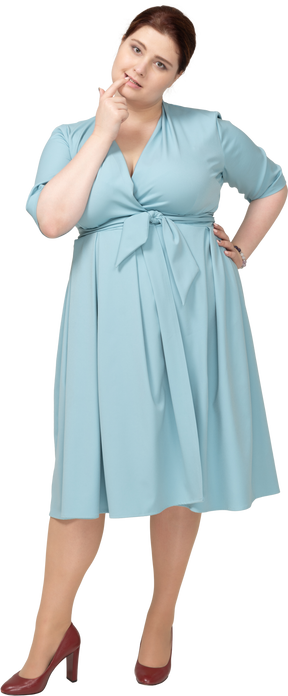 Вид спереди женщины в синем платье, кусающей палец