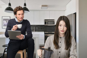 Man with tablet drinking coffee and woman holding moka pot