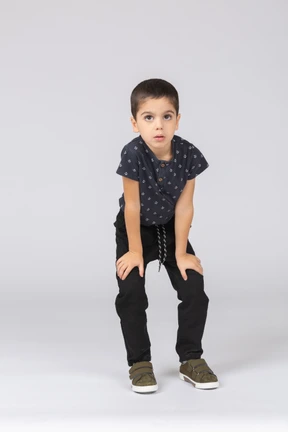 Front view of a cute boy squatting and looking at camera