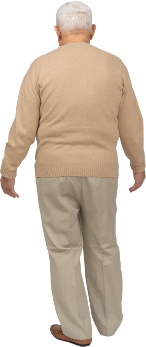 Rear view of an old man in casual clothes standing with outstretched arms