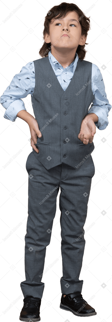 Front view of a cute boy in grey suit posing with hand on hip and looking up