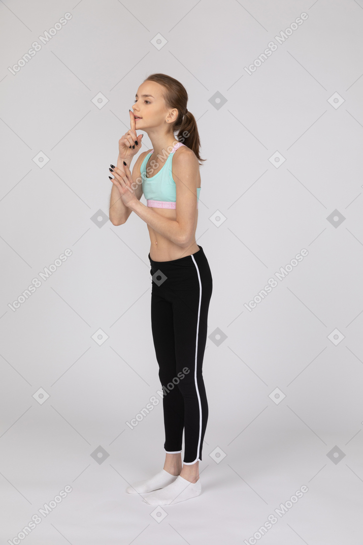 Una adolescente en ropa deportiva mostrando un gesto de silencio.