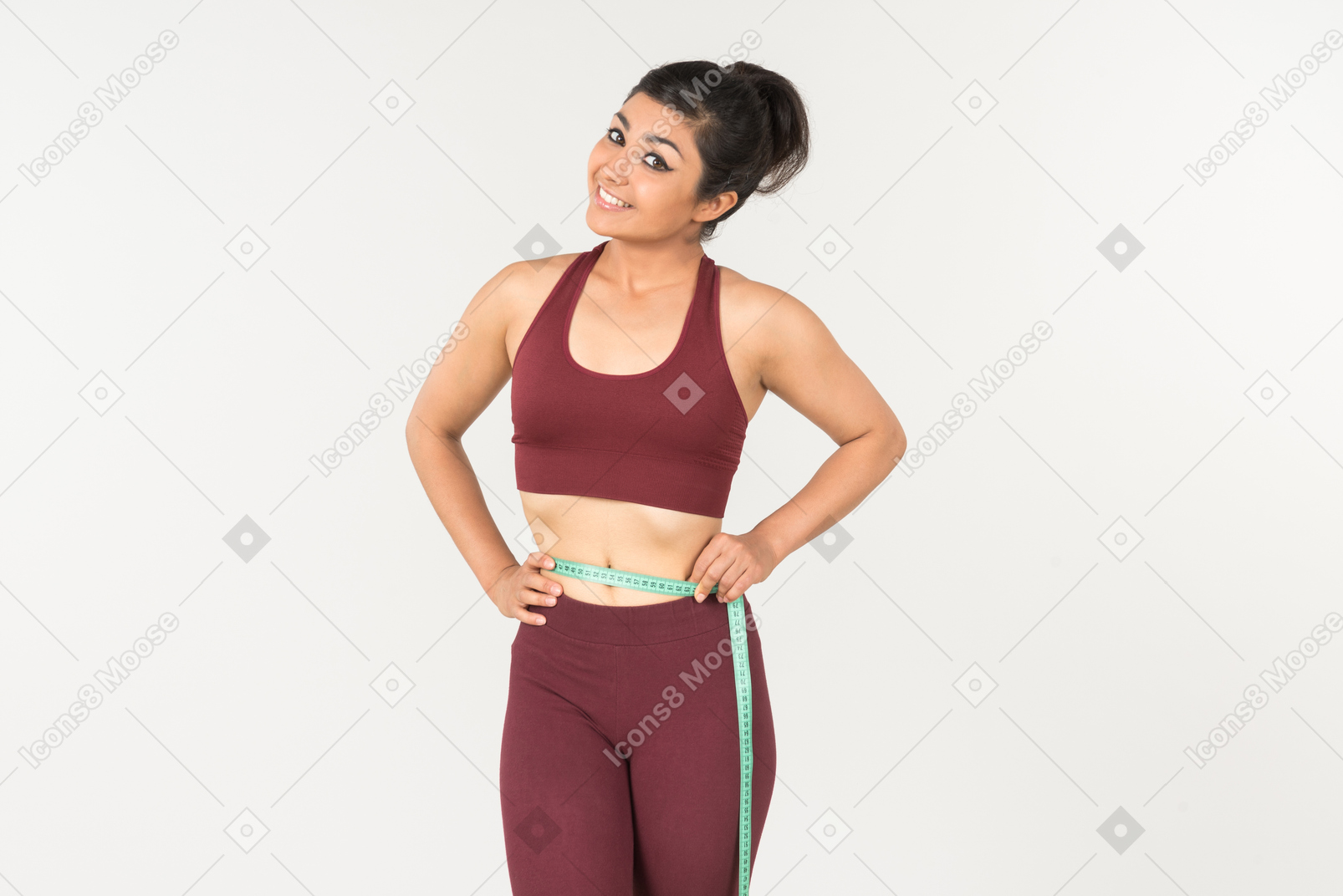 Young indian woman in sporstweat measuring her waist