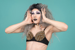Drag queen holding their face with both hands