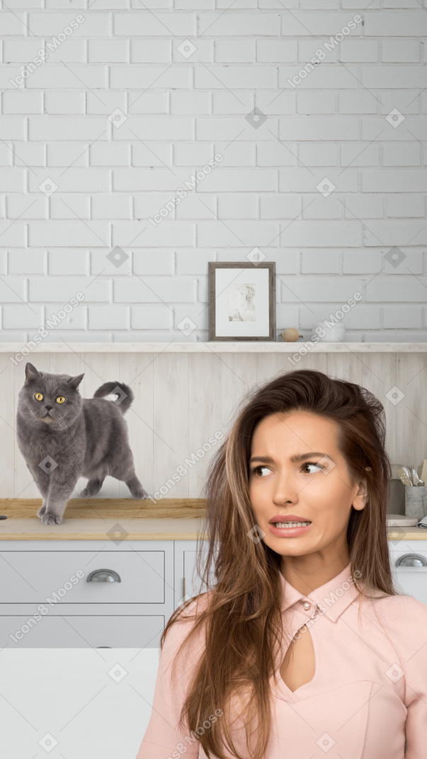 A woman standing in a kitchen with a cat on the counter