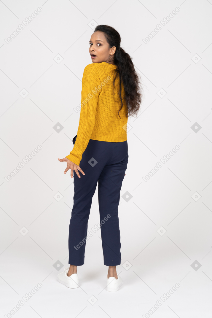 Rear view of an impressed girl in casual clothes looking at camera