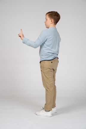 Vue latérale d'un garçon pointant vers le haut avec le doigt