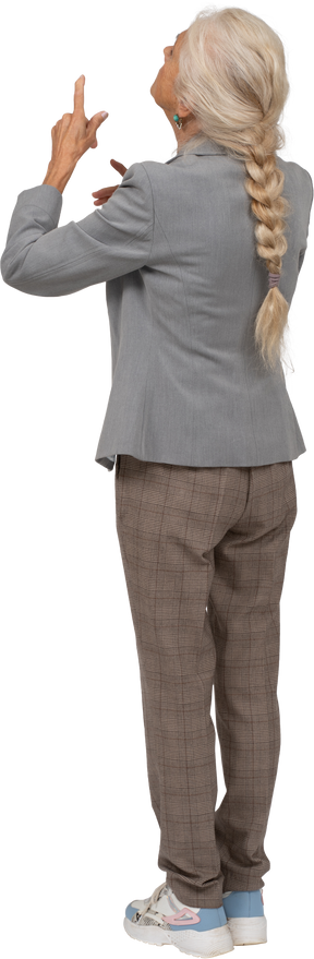 Rear view of an old lady in suit pointing up with finger