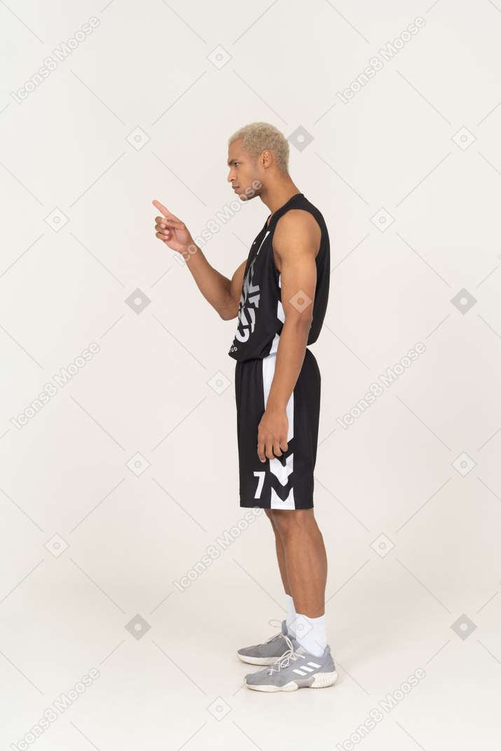 Vista lateral de um jovem jogador de basquete apontando o dedo