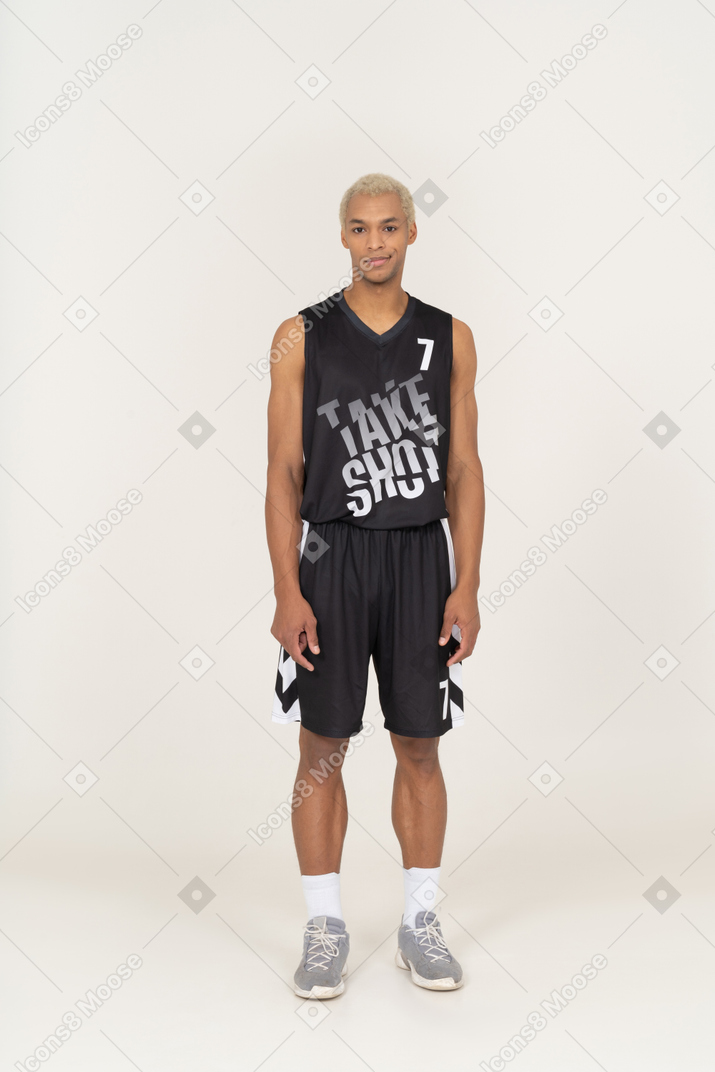一个傻笑的年轻男篮球运动员站着不动的前视图