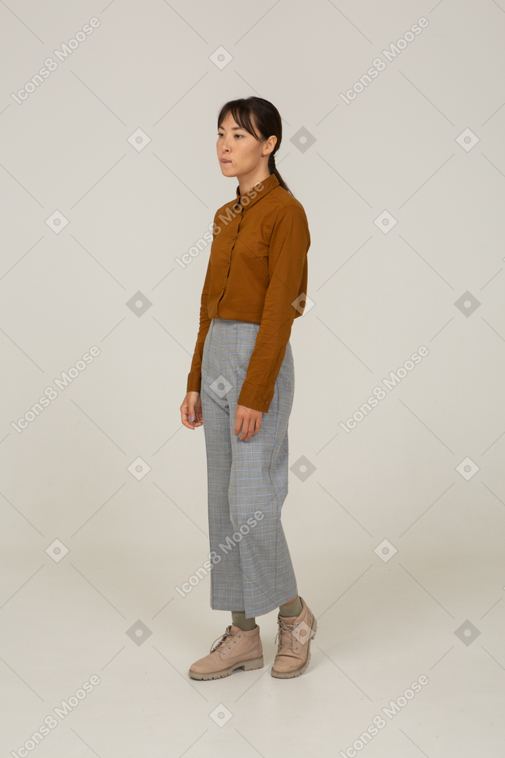 Three-quarter view of a young asian female in breeches and blouse biting lip