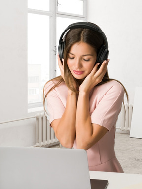 A woman wearing headphones while using a laptop