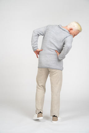 Back view of a man standing with hands on waist and looking down