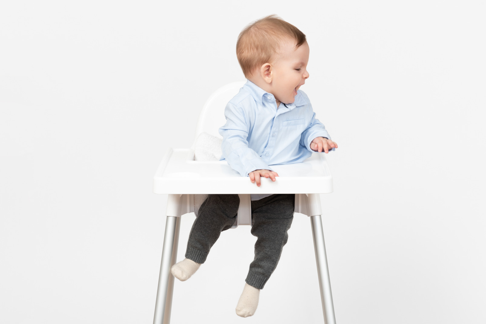 Adorable laughing baby boy sitting in highchair