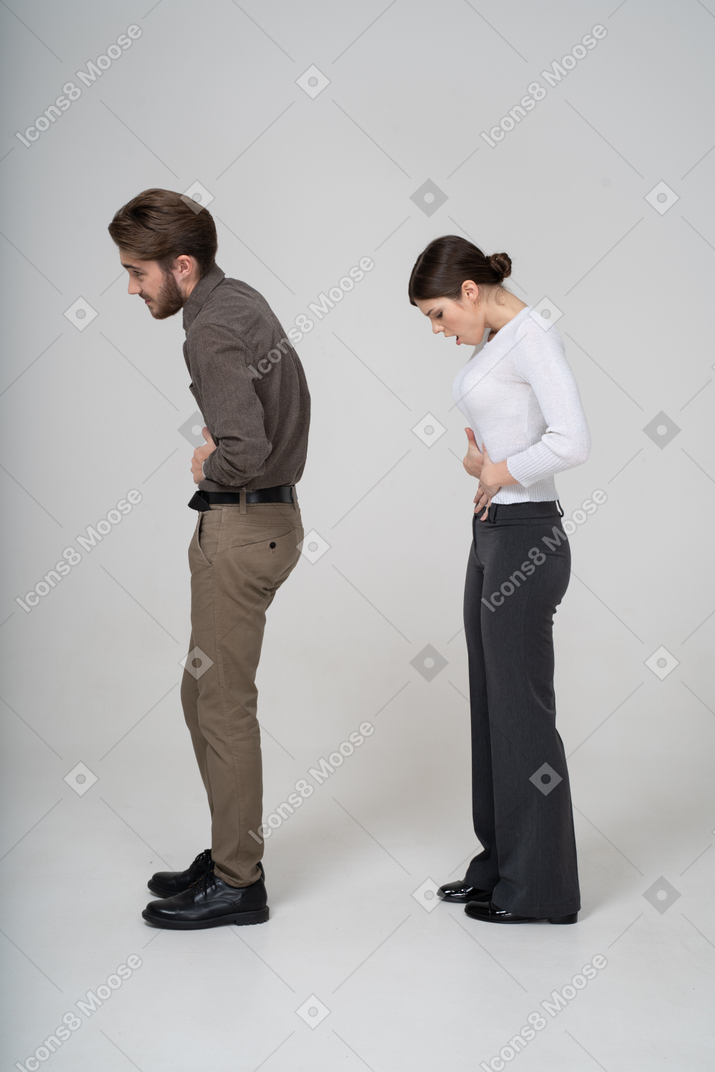 Side view of a young couple in office clothing touching stomach
