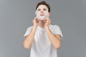 Vue de face d'un jeune homme mettant un masque facial