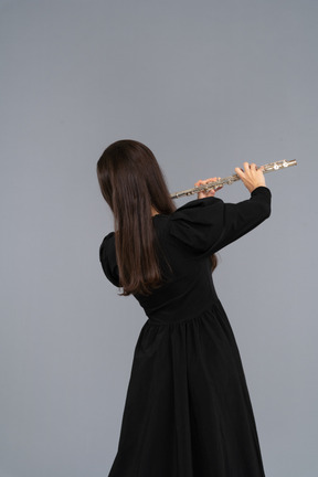 Black view of a young lady in black dress playing the flute