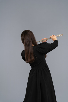 Imagem negra de uma jovem de vestido preto tocando flauta