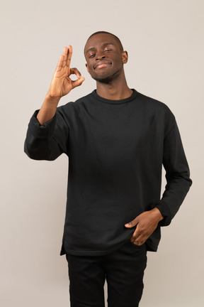 Smiling man standing and showing ok gesture