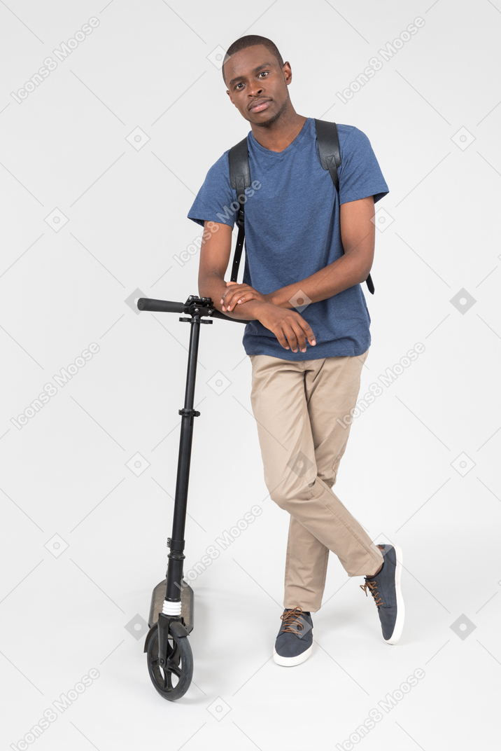 Black male city tourist leaning on scooter