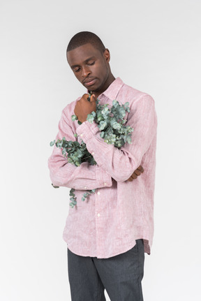 Good looking young man holding green branches