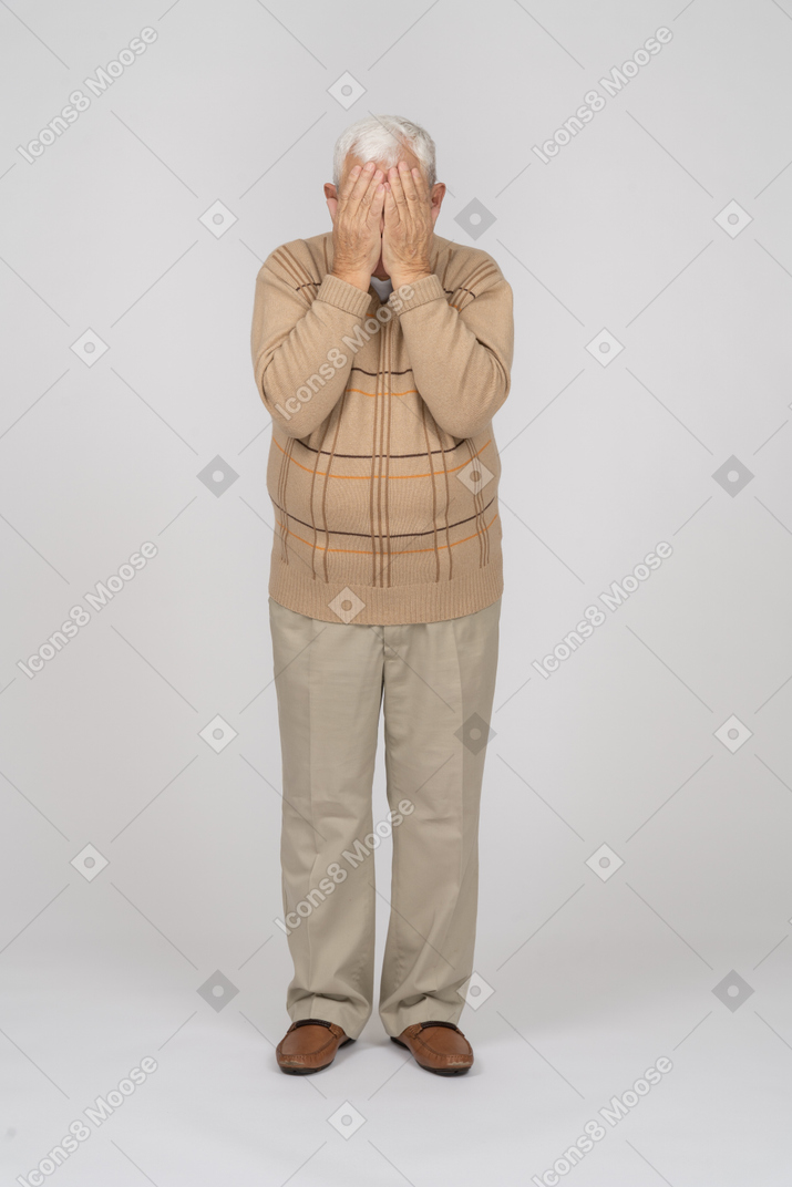 Vista frontale di un vecchio in abiti casual che coprono il viso con le mani