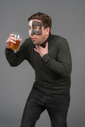 Vista de tres cuartos de un fanático del fútbol masculino sorprendido sosteniendo una cerveza