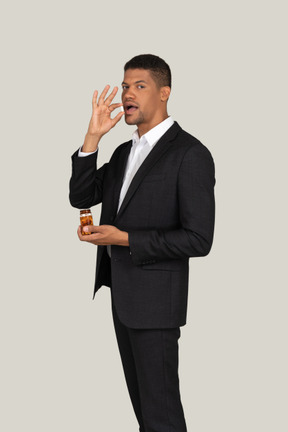African american in black suit holding bottle of pills