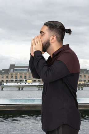 Man shouting through hands near water