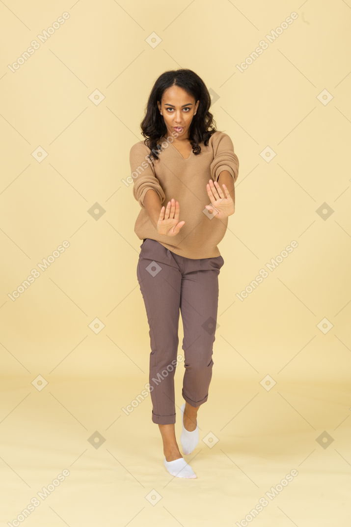 Front view of an unwilling dark-skinned young female outstretching hands