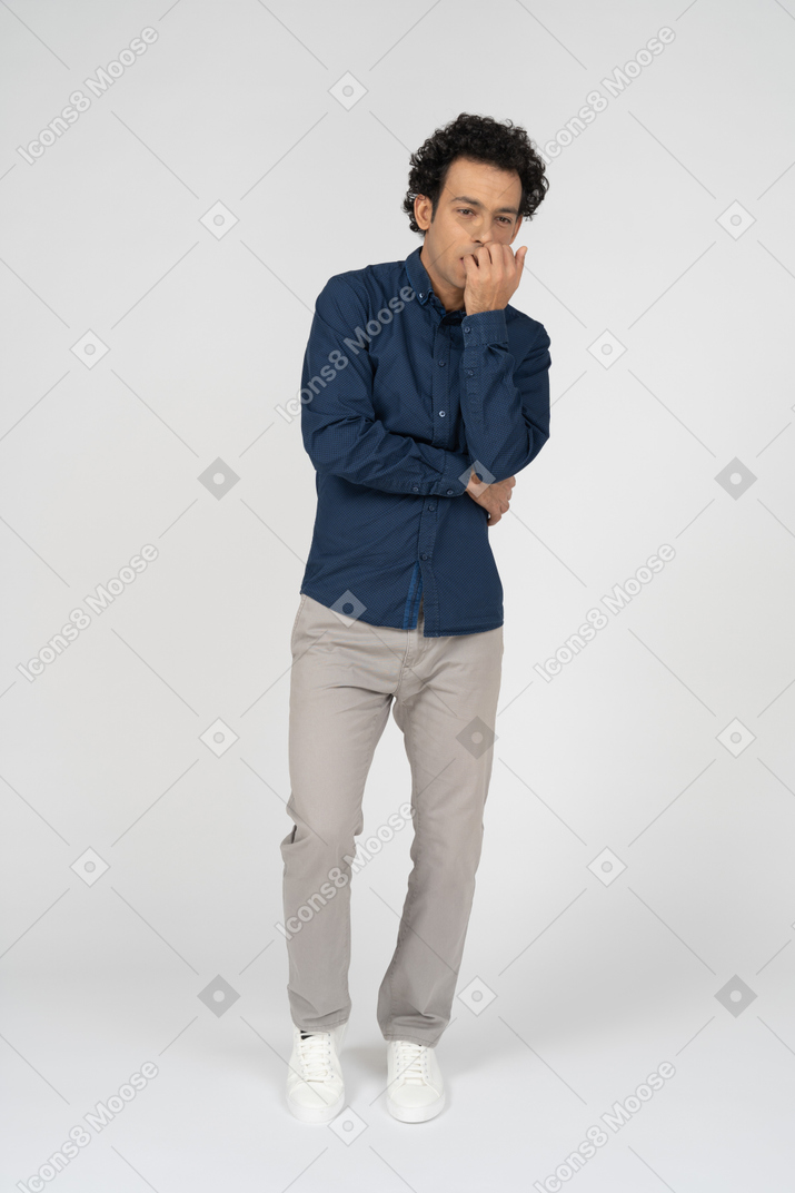 Vista frontal de un hombre en ropa casual mordiéndose los dedos