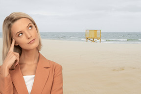 A woman standing on a beach with a lifeguard tower in the background