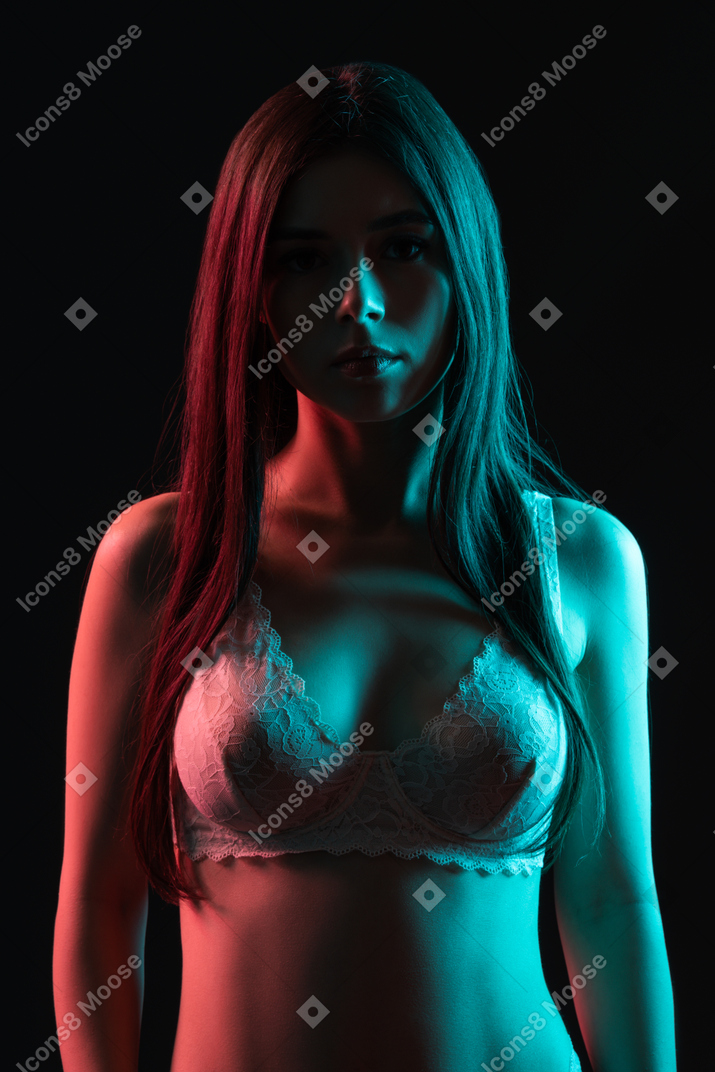 A sensual portrait of a young female standing in neon lights