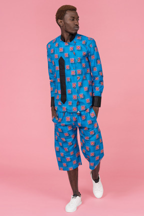 Black man in blue pajamas standing on pink background