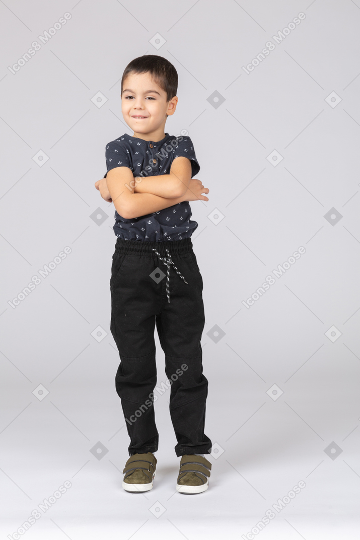 Vista frontal de um menino fofo posando com os braços cruzados
