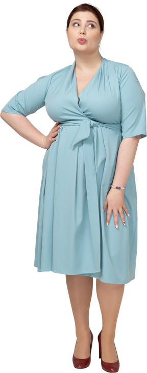 Vista frontal de uma mulher de vestido azul posando com a mão no quadril